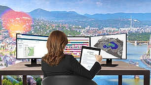 Professional reviewing license application and spectrum coverage data on dual monitors with compliance certificate