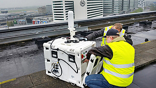 Technicians installing rooftop spectrum monitoring equipment for continuous remote signal analysis